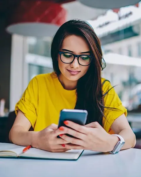 A new physician, a Hispanic woman, casually dressed using her cell phone researching compensation rates for new doctor.